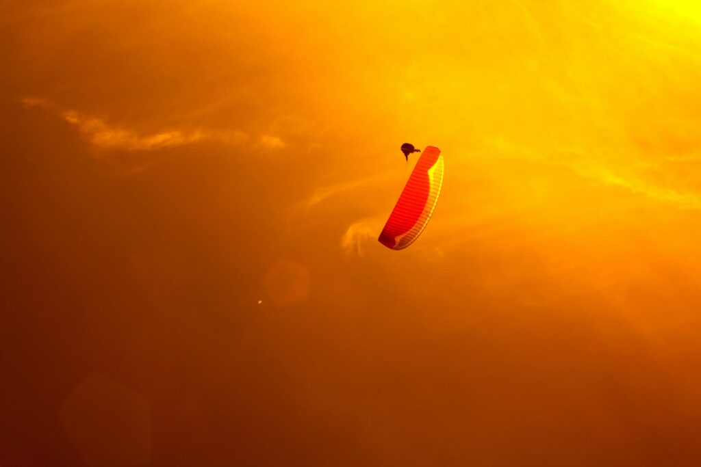 person paragliding under orange skies